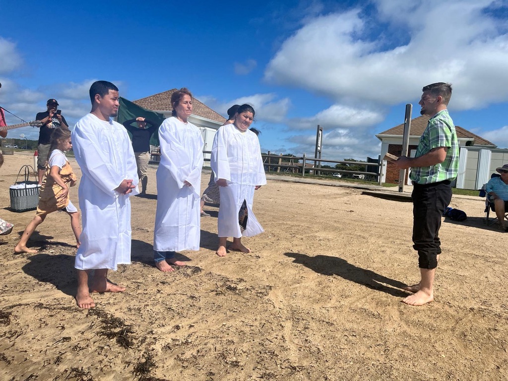 El pastor Ian con tres miembros antes de sus bautismos en la playa